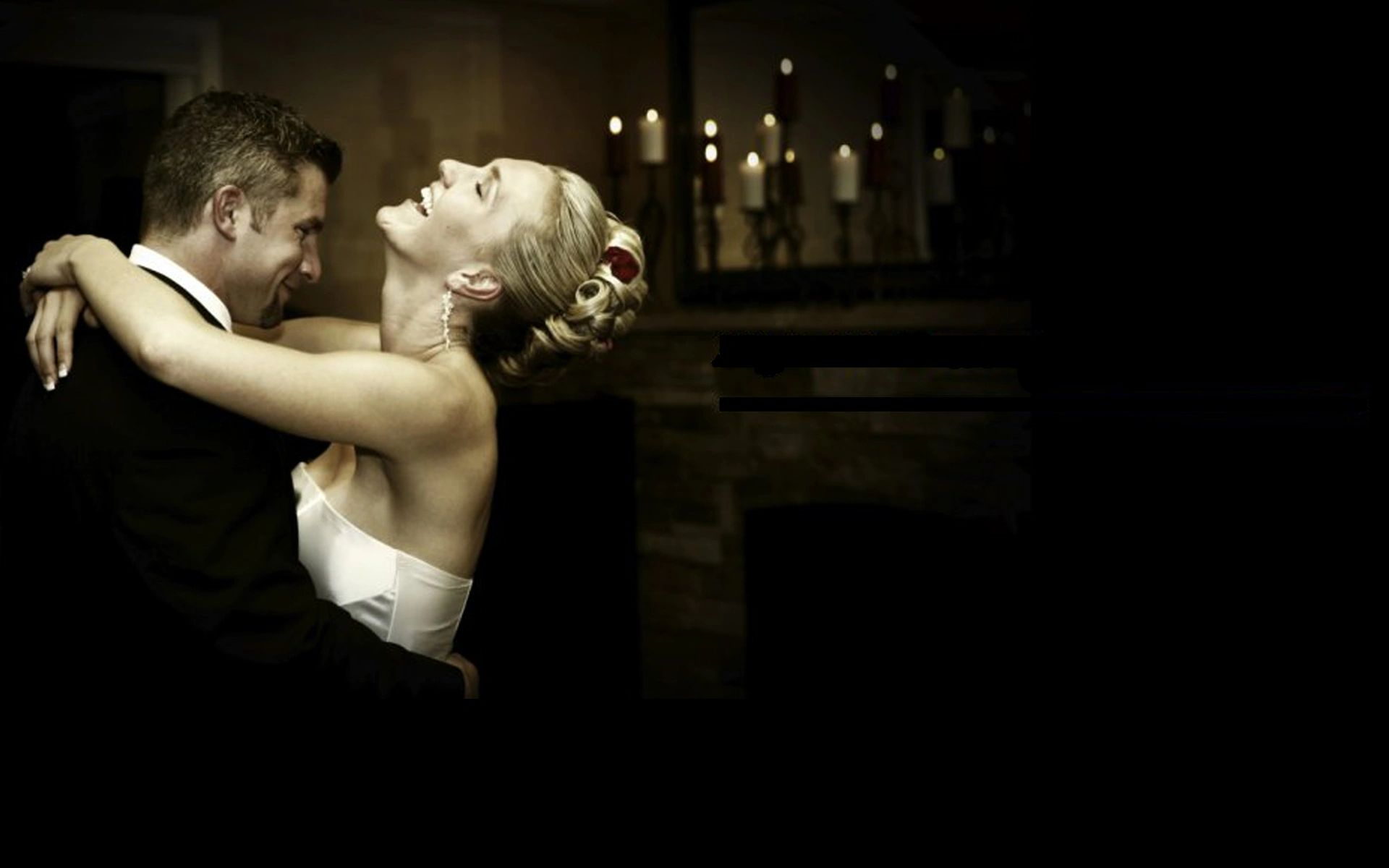 A couple's first dance in a darkened room, lit from one side.