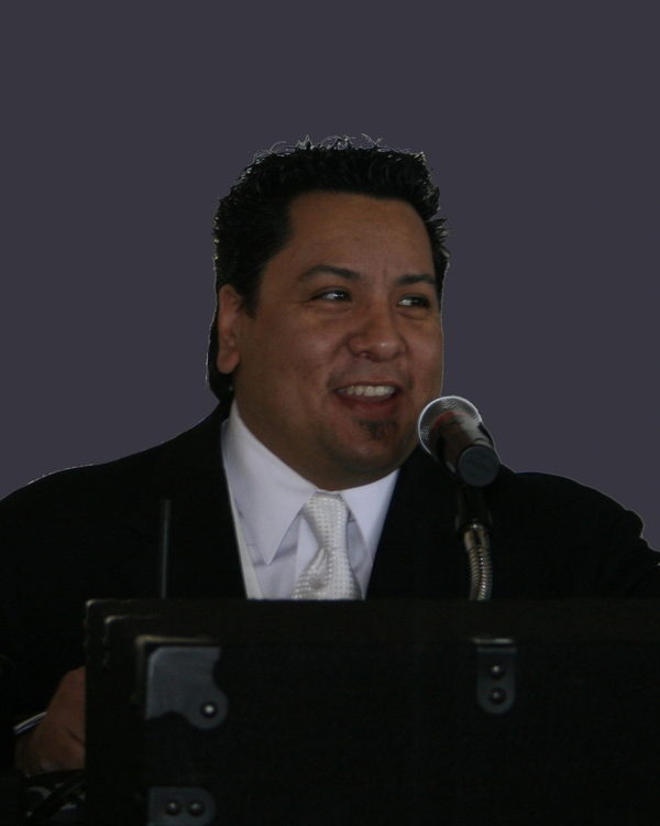 DJ George at a podium microphone.